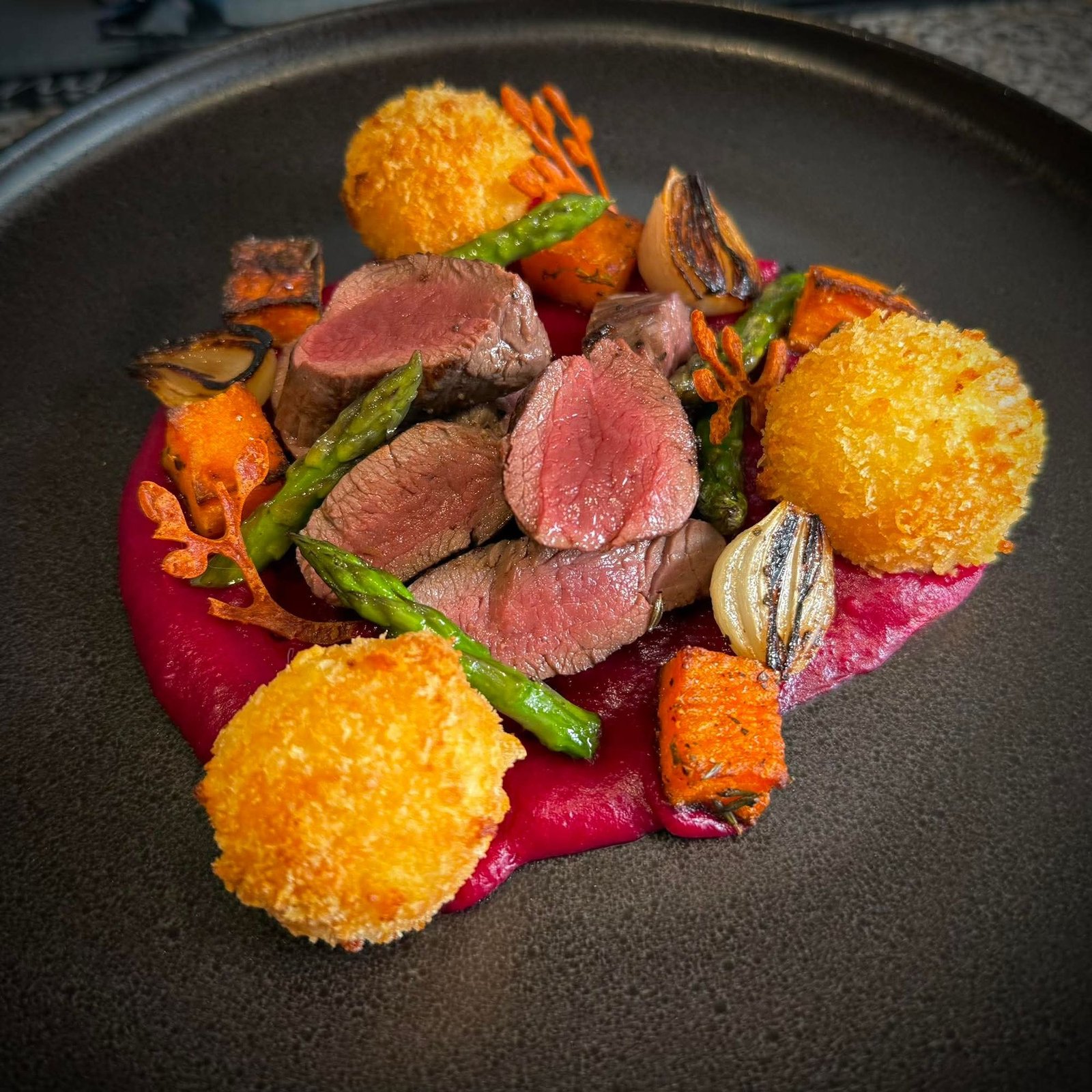 Sliced venison with beet purée, crisp croquettes and charred asparagus, plated by Chef Maureen